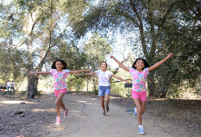 Three girls running in nature. It's a spring break bucket list for visiting Claremont.