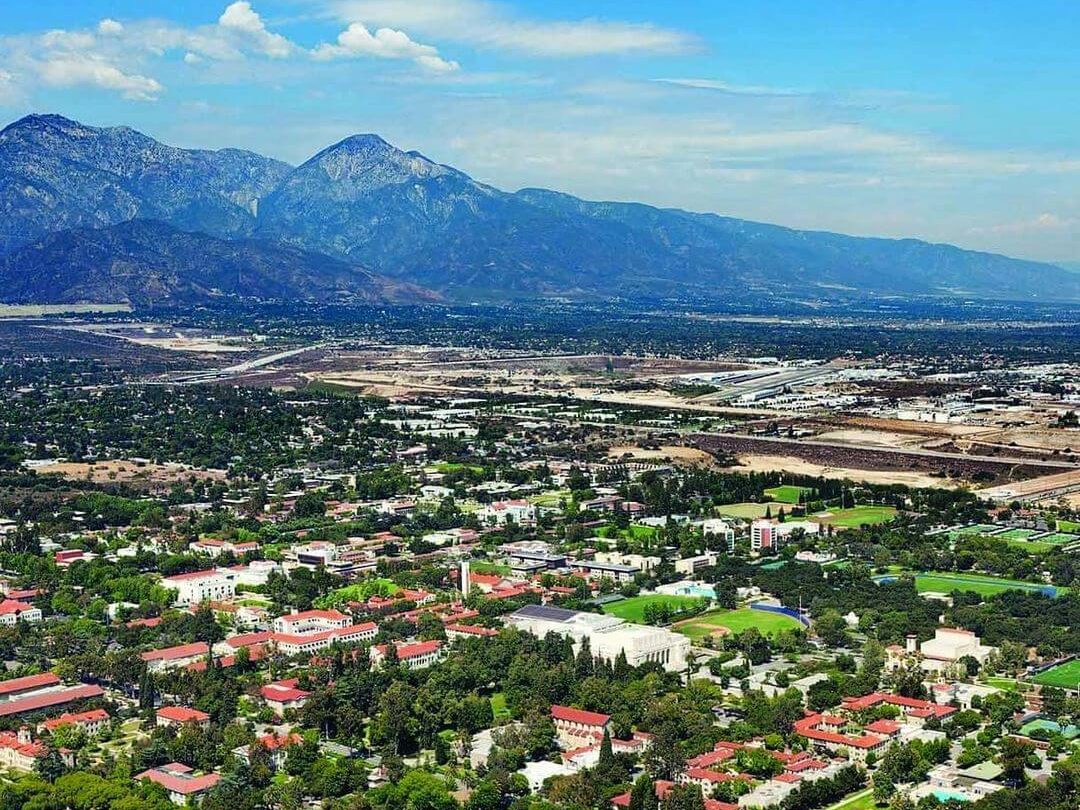 Overhead city view of Claremont city with mountain range in the back and blue sky above.