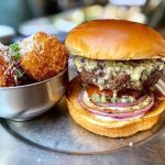 A burger on a plate with a side at Eureka! Claremont