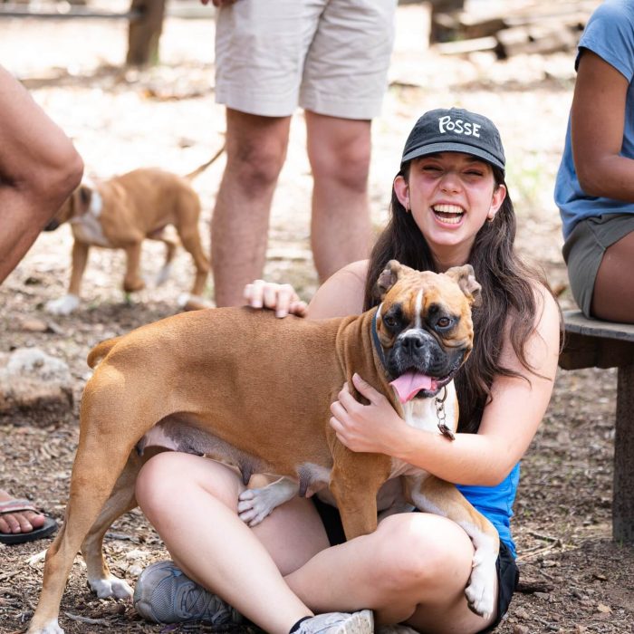 Girl at pet friendly dog park hugging her big boxer hound and both are smiling.