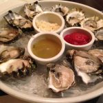 Fresh Oysters on a plate with three dipping sauces.