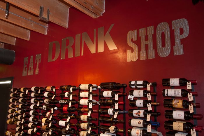 Wine bottles and a wall that says Eat, Drink, Shop to celebrate Autumn in Claremont