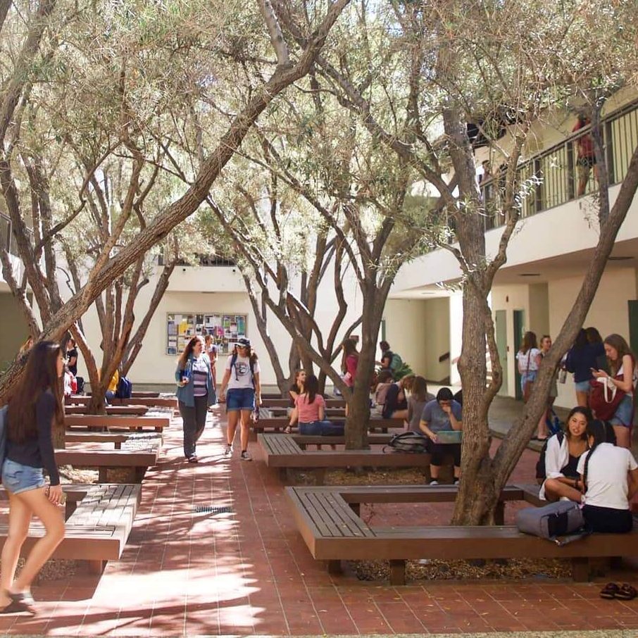 Courtyard full of trees and students walking between two buildings at Scripps College